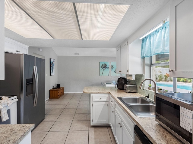 9109 134th Way, Seminole, FL 33776 - kitchen featuring stainless steel appliances, white cabinets, a peninsula, and light countertops