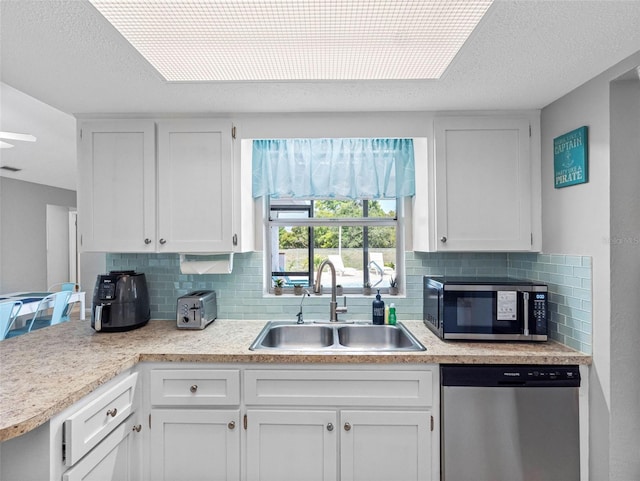 9109 134th Way, Seminole, FL 33776 - kitchen with appliances with stainless steel finishes, backsplash, white cabinetry, and a textured ceiling