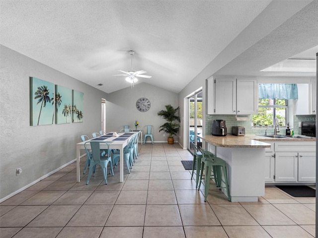 9109 134th Way, Seminole, FL 33776 - dining area with ceiling fan, a textured ceiling, light tile patterned floors, vaulted ceiling, and a textured wall
