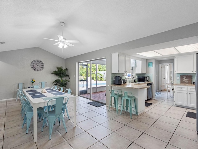 9109 134th Way, Seminole, FL 33776 - dining area featuring vaulted ceiling, ceiling fan, light tile patterned flooring, and a textured ceiling