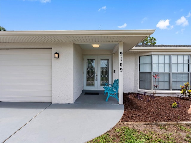 9109 134th Way, Seminole, FL 33776 - property entrance featuring stucco siding, french doors, an attached garage, and driveway