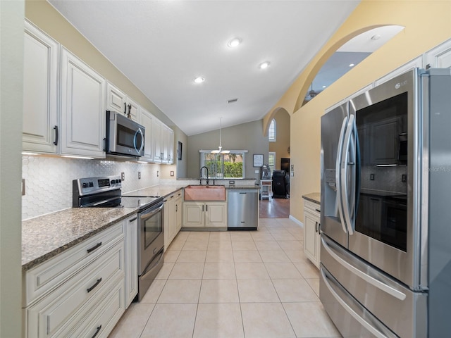 8222 Haven Harbour Way, Bradenton, FL 34212 - kitchen featuring stainless steel appliances, a peninsula, decorative backsplash, vaulted ceiling, and light stone counters
