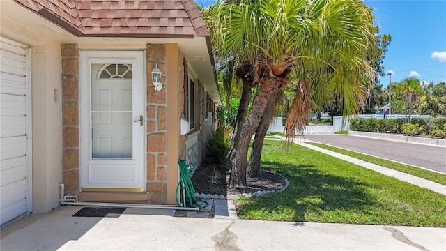 1102 Cara Dr, Largo, FL 33771 - property entrance featuring roof with shingles and a yard