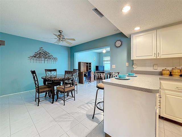 1102 Cara Dr, Largo, FL 33771 - kitchen featuring a textured ceiling, a ceiling fan, white cabinetry, light countertops, and decorative backsplash