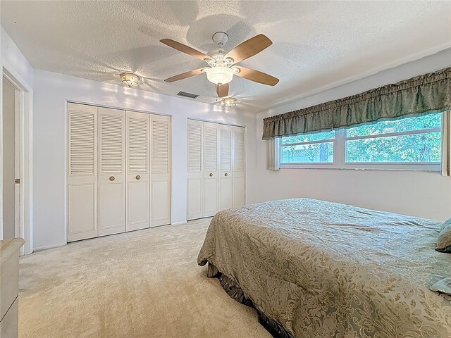 1102 Cara Dr, Largo, FL 33771 - bedroom with light carpet, two closets, a textured ceiling, and a ceiling fan