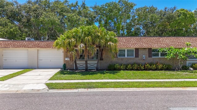 1102 Cara Dr, Largo, FL 33771 - view of front of house featuring a front lawn, driveway, roof with shingles, and an attached garage