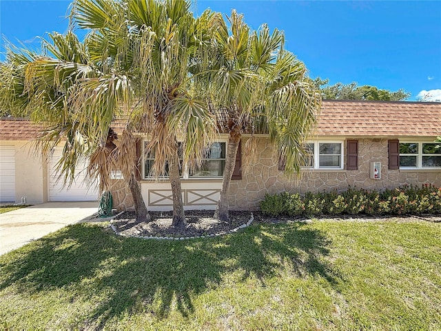 1102 Cara Dr, Largo, FL 33771 - view of front facade featuring stone siding, a front yard, a shingled roof, and concrete driveway