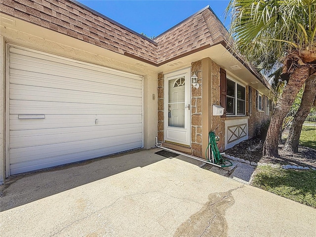 1102 Cara Dr, Largo, FL 33771 - view of exterior entry featuring roof with shingles, mansard roof, concrete driveway, and a garage
