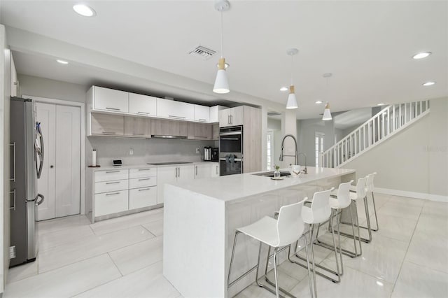 15722 Gardenside Ln, Tampa, FL 33624 - kitchen with appliances with stainless steel finishes, recessed lighting, a kitchen island with sink, light countertops, and a breakfast bar