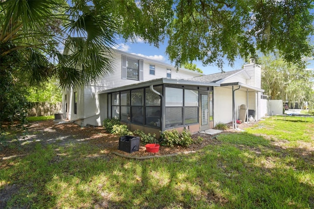 15722 Gardenside Ln, Tampa, FL 33624 - back of property featuring a sunroom, a chimney, and stucco siding