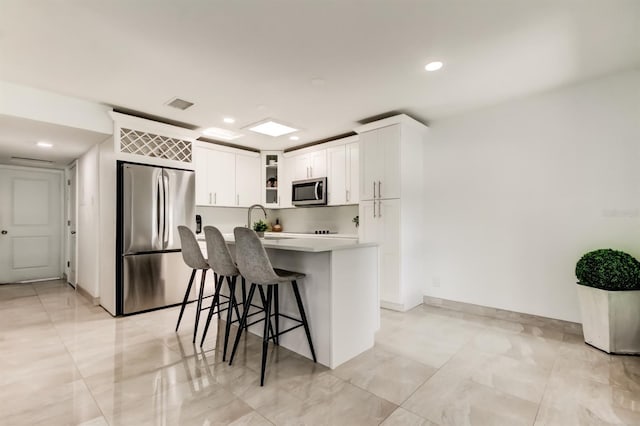 4727 Town N Country Blvd, Tampa, FL 33615 - kitchen featuring appliances with stainless steel finishes, light countertops, a breakfast bar area, white cabinets, and recessed lighting