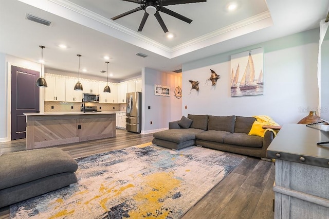 7683 Summerland Cv, Lakewood Ranch, FL 34202 - living area featuring a ceiling fan, dark wood finished floors, ornamental molding, recessed lighting, and a tray ceiling