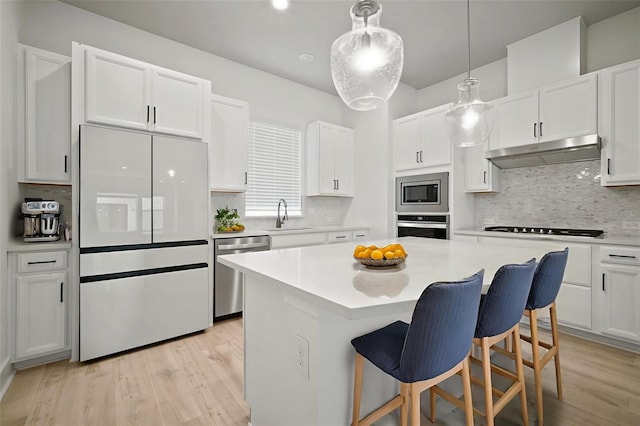 2511 N Grady Ave Unit 43, Tampa, FL 33607 - kitchen with stainless steel appliances, under cabinet range hood, light wood-style floors, and white cabinetry
