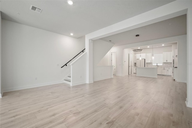 2511 N Grady Ave Unit 43, Tampa, FL 33607 - unfurnished living room with light wood-style flooring, stairway, and recessed lighting