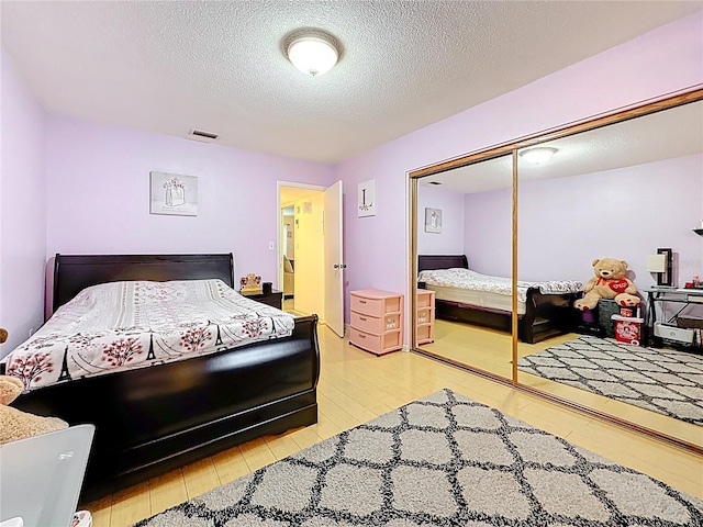 5870 38th Ave N Unit 44, Saint Petersburg, FL 33710 - bedroom featuring light wood finished floors, a textured ceiling, and a closet