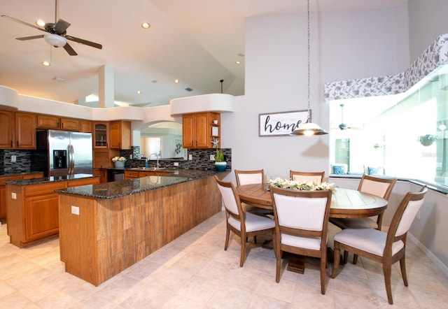 916 Bunker View Dr, Apollo Beach, FL 33572 - kitchen with appliances with stainless steel finishes, brown cabinets, decorative backsplash, a center island, and high vaulted ceiling