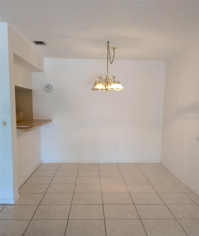 642 Bird Bay Dr E Unit 205, Venice, FL 34285 - empty room with light tile patterned floors, a chandelier, and a textured ceiling