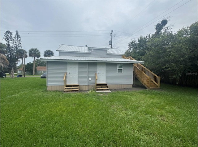 1512 7th St, Saint Cloud, FL 34769 - back of house featuring entry steps, a yard, stairs, and a metal roof
