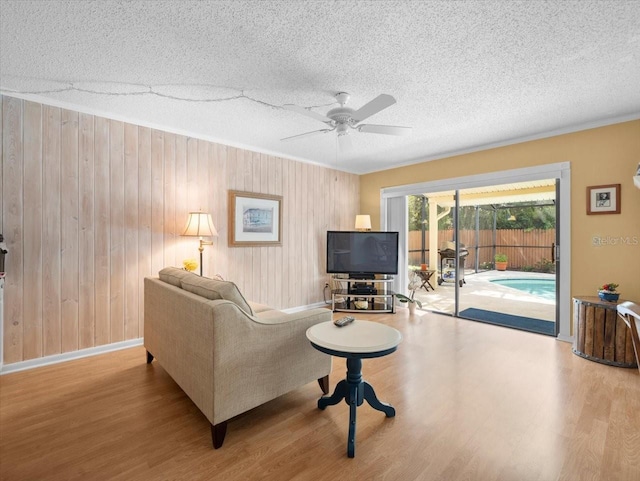 15711 Springmoss Ln, Tampa, FL 33624 - living area featuring wood finished floors, ceiling fan, a textured ceiling, wood walls, and crown molding