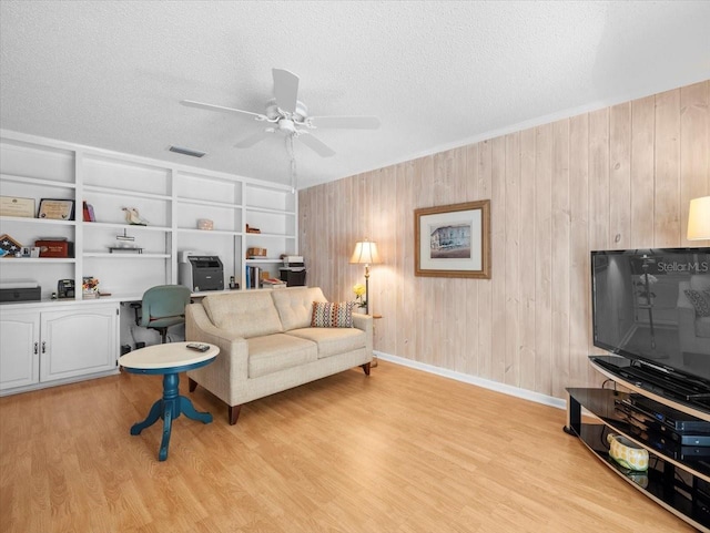15711 Springmoss Ln, Tampa, FL 33624 - living room featuring a ceiling fan, a textured ceiling, light wood-type flooring, and wood walls
