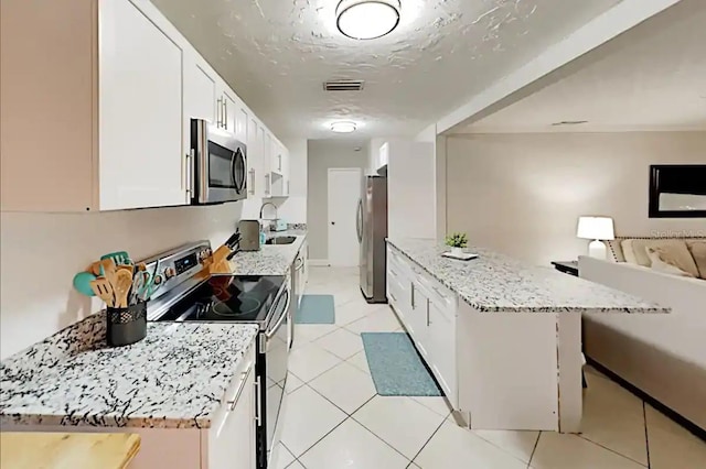 4505 S Clark Ave, Tampa, FL 33611 - kitchen featuring appliances with stainless steel finishes, open floor plan, white cabinets, and light stone countertops