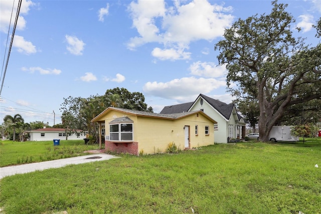 1560 Connecticut Ave NE, Saint Petersburg, FL 33703 - view of side of property featuring concrete block siding, a lawn, and roof with shingles
