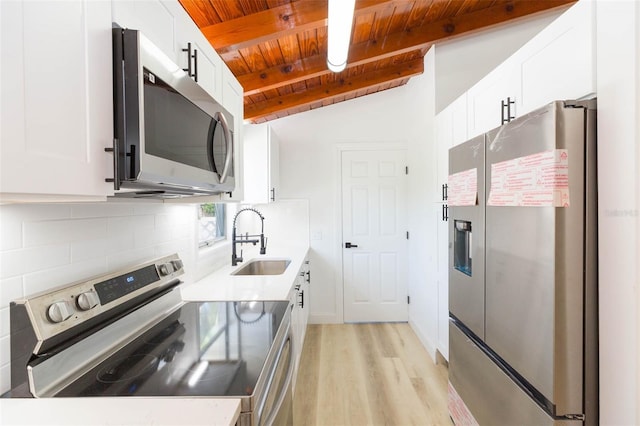 9445 Cardy St, New Port Richey, FL 34654 - kitchen featuring appliances with stainless steel finishes, wood ceiling, light wood finished floors, tasteful backsplash, and white cabinets
