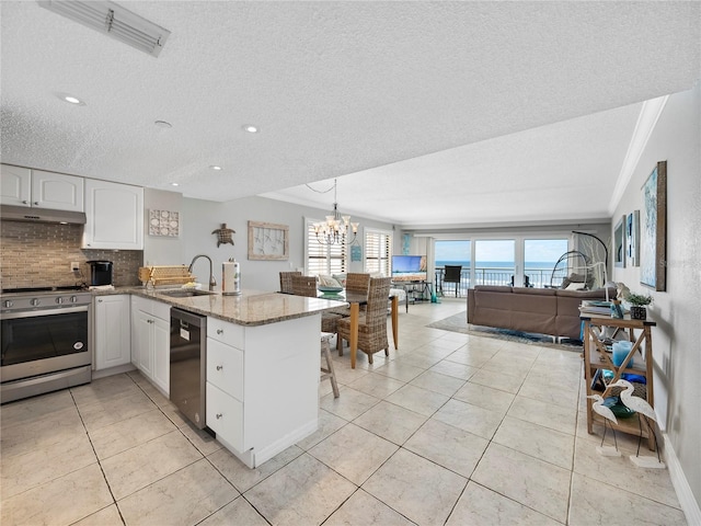 19440 Gulf Blvd Unit 301, Indian Rocks Beach, FL 33785 - kitchen with appliances with stainless steel finishes, a peninsula, under cabinet range hood, backsplash, and light stone countertops