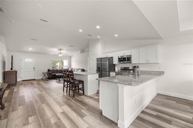 231 Marion Oaks Trl, Ocala, FL 34473 - kitchen with stainless steel appliances, a kitchen breakfast bar, white cabinetry, vaulted ceiling, and open floor plan