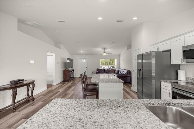 231 Marion Oaks Trl, Ocala, FL 34473 - kitchen featuring appliances with stainless steel finishes, a kitchen island, white cabinets, light wood-style floors, and vaulted ceiling