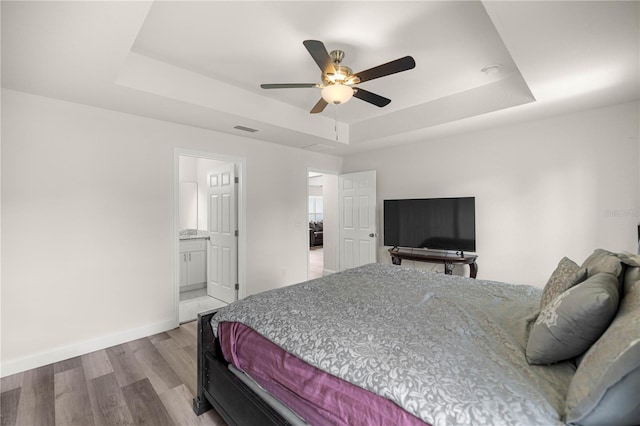 231 Marion Oaks Trl, Ocala, FL 34473 - bedroom with a tray ceiling, wood finished floors, a ceiling fan, and ensuite bathroom