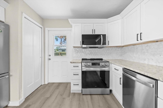 4718 W Oklahoma Ave, Tampa, FL 33616 - kitchen with appliances with stainless steel finishes, light wood-type flooring, light stone countertops, white cabinetry, and tasteful backsplash