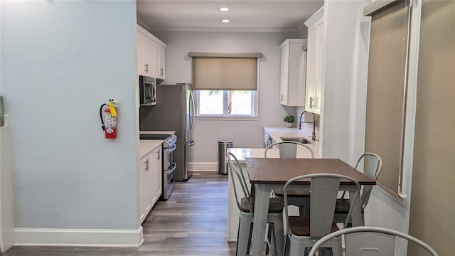 5000 Culbreath Key Way Unit 1-220, Tampa, FL 33611 - kitchen featuring appliances with stainless steel finishes, white cabinets, wood finished floors, light countertops, and ornamental molding