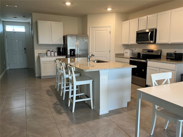 17807 Canopy Pl, Bradenton, FL 34211 - kitchen featuring appliances with stainless steel finishes, a center island with sink, white cabinets, light stone counters, and recessed lighting