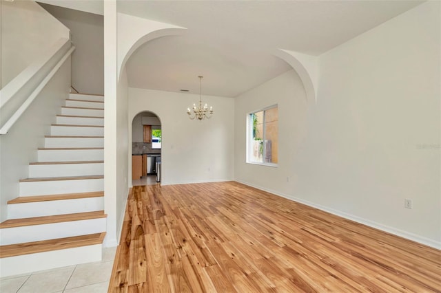 1734 Mapleleaf Blvd, Oldsmar, FL 34677 - unfurnished living room featuring arched walkways, light wood finished floors, stairway, and a chandelier