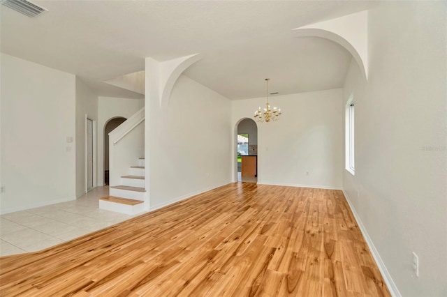 1734 Mapleleaf Blvd, Oldsmar, FL 34677 - spare room with arched walkways, light wood-type flooring, a chandelier, and stairs