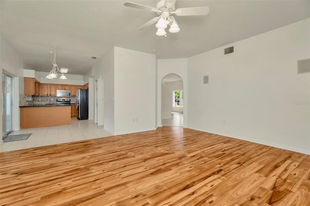 1734 Mapleleaf Blvd, Oldsmar, FL 34677 - unfurnished living room with arched walkways, light wood-type flooring, and ceiling fan
