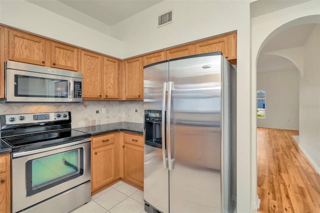 1734 Mapleleaf Blvd, Oldsmar, FL 34677 - kitchen with appliances with stainless steel finishes, arched walkways, dark countertops, and decorative backsplash