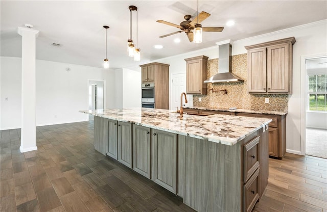 6728 Sutton Oaks Ln, Zephyrhills, FL 33541 - kitchen featuring wall chimney range hood, decorative columns, double oven, a ceiling fan, and dark wood-style floors
