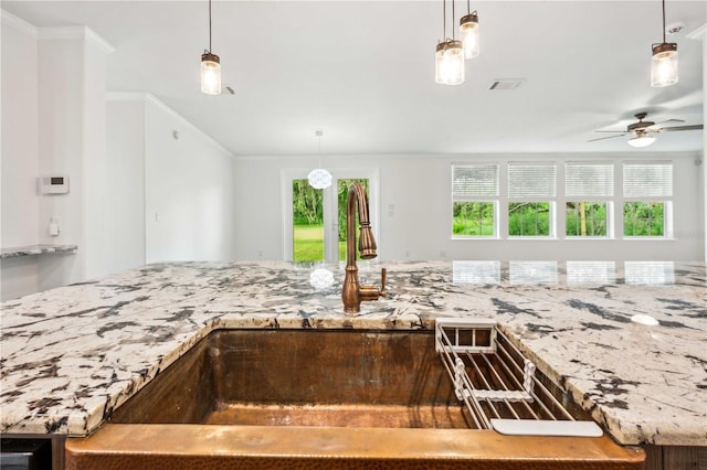 6728 Sutton Oaks Ln, Zephyrhills, FL 33541 - kitchen with crown molding, a ceiling fan, light stone counters, and pendant lighting