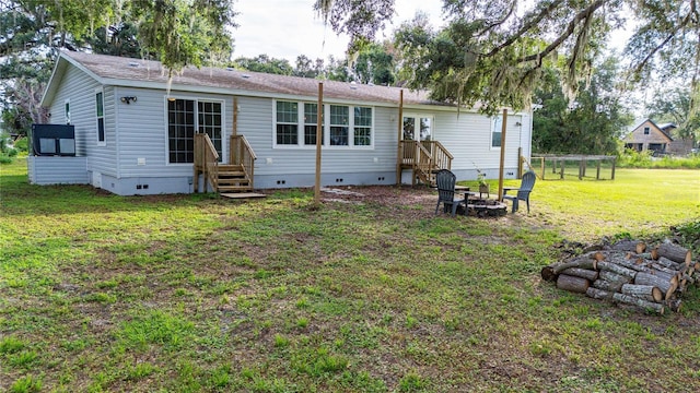 6728 Sutton Oaks Ln, Zephyrhills, FL 33541 - back of house featuring crawl space, a lawn, and a fire pit