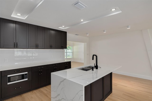 1723 Cypress Ave, Belleair, FL 33756 - kitchen with stainless steel microwave, light wood-style floors, dark cabinetry, light stone counters, and recessed lighting