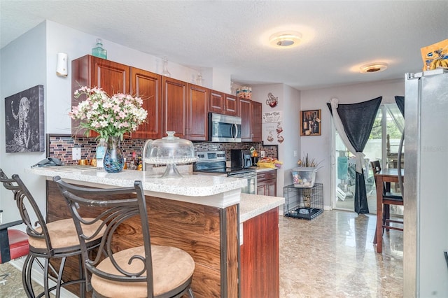 1827 Peaceful Palm St, Ruskin, FL 33570 - kitchen featuring appliances with stainless steel finishes, decorative backsplash, light countertops, a peninsula, and a kitchen bar