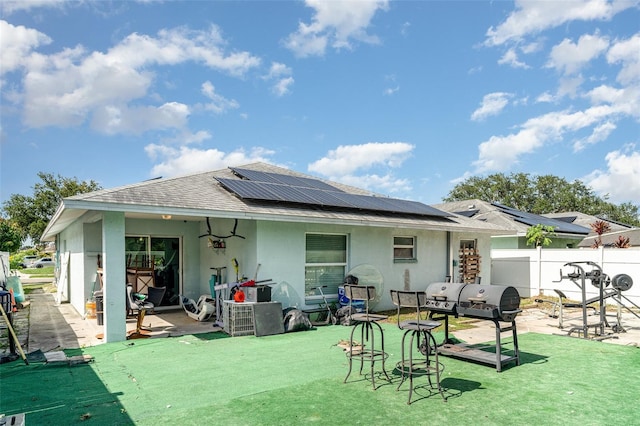 1827 Peaceful Palm St, Ruskin, FL 33570 - back of property with a patio, stucco siding, roof mounted solar panels, and roof with shingles