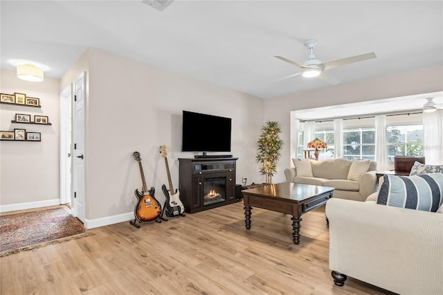 1251 Fairway Dr, Dunedin, FL 34698 - living area with light wood-type flooring, a ceiling fan, and a glass covered fireplace