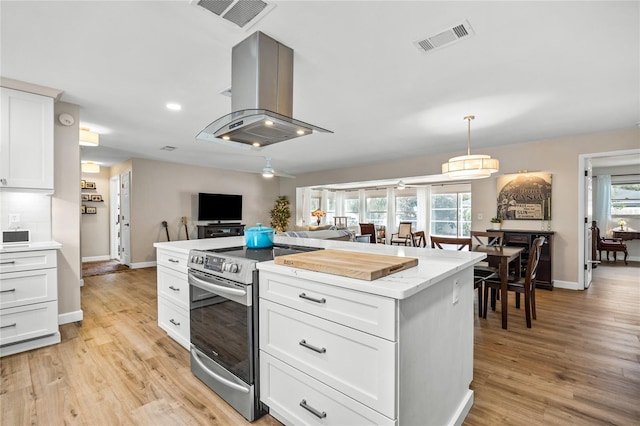 1251 Fairway Dr, Dunedin, FL 34698 - kitchen featuring stainless steel electric range, light wood-type flooring, white cabinetry, pendant lighting, and a kitchen island