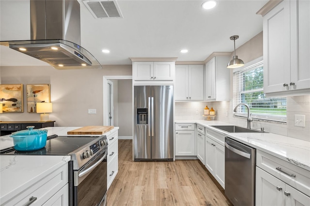 1251 Fairway Dr, Dunedin, FL 34698 - kitchen with stainless steel appliances, island exhaust hood, light wood-type flooring, white cabinetry, and decorative backsplash