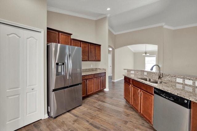 11309 Langworth Hill Ln, Riverview, FL 33579 - kitchen featuring appliances with stainless steel finishes, arched walkways, ornamental molding, wood finished floors, and light stone countertops