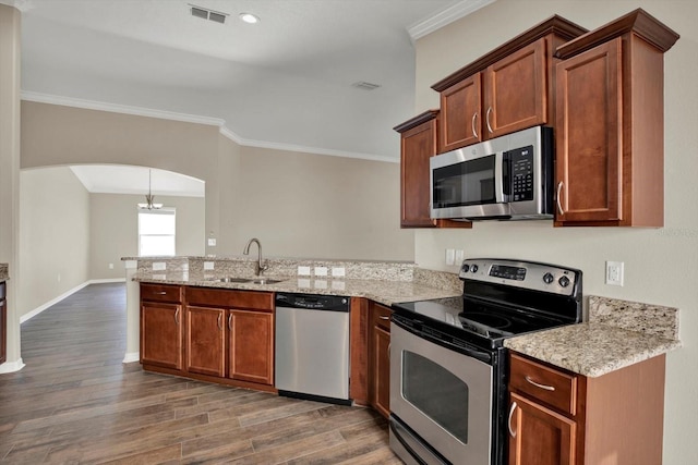 11309 Langworth Hill Ln, Riverview, FL 33579 - kitchen featuring stainless steel appliances, a peninsula, arched walkways, wood finished floors, and crown molding