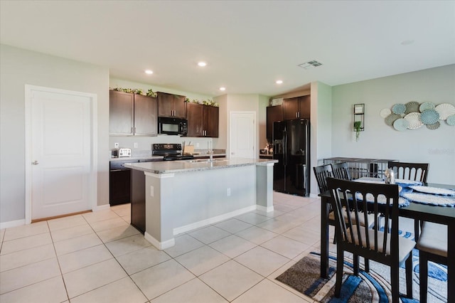 17156 Yellow Pine St, Wimauma, FL 33598 - kitchen with black appliances, dark brown cabinets, a center island with sink, recessed lighting, and light tile patterned floors